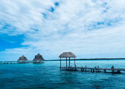 brown wooden beach house on blue sea under blue sky and white clouds during daytime